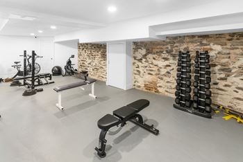 A gym with a variety of equipment including weights and a bench.