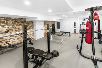 A gym with a variety of equipment including a squat rack, bench, and a punching bag.