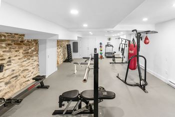 A well-equipped gym with a variety of exercise machines and a stone wall.