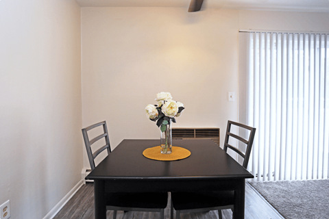 a dining room with a table and chairs and a vase of flowers