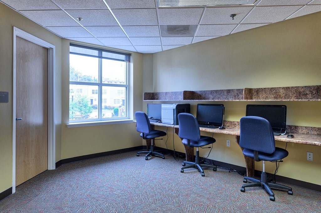 a large office with three desks with computers and chairs