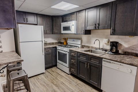 an updated kitchen with white appliances and dark cabinets