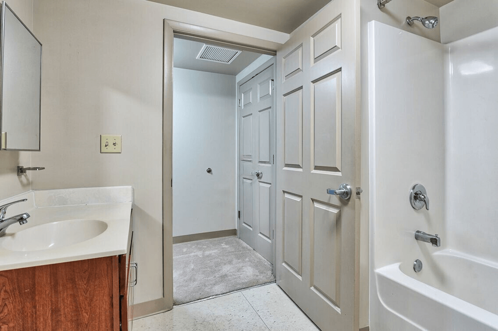 a bathroom with an open door and a sink and a shower