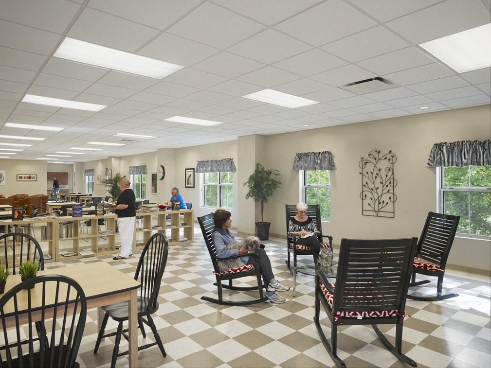a woman sits in a chair with her dog in a waiting room at a hospital