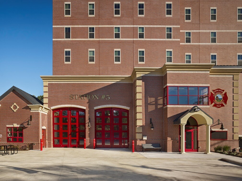 a fire station with red doors in front of a brick building