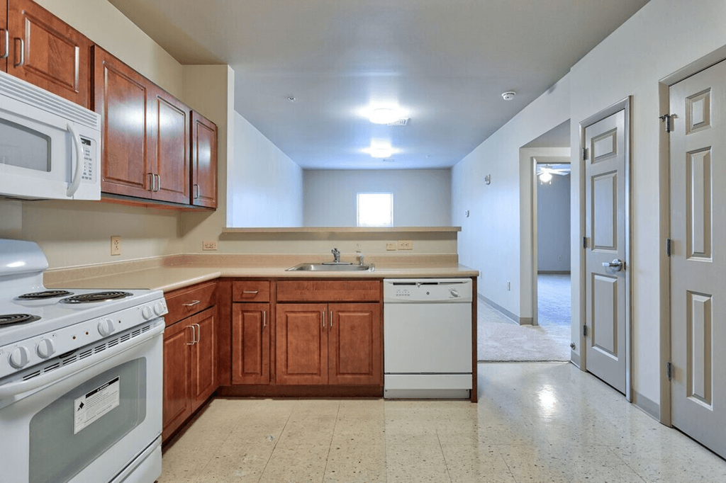 an empty kitchen with white appliances and wooden cabinets