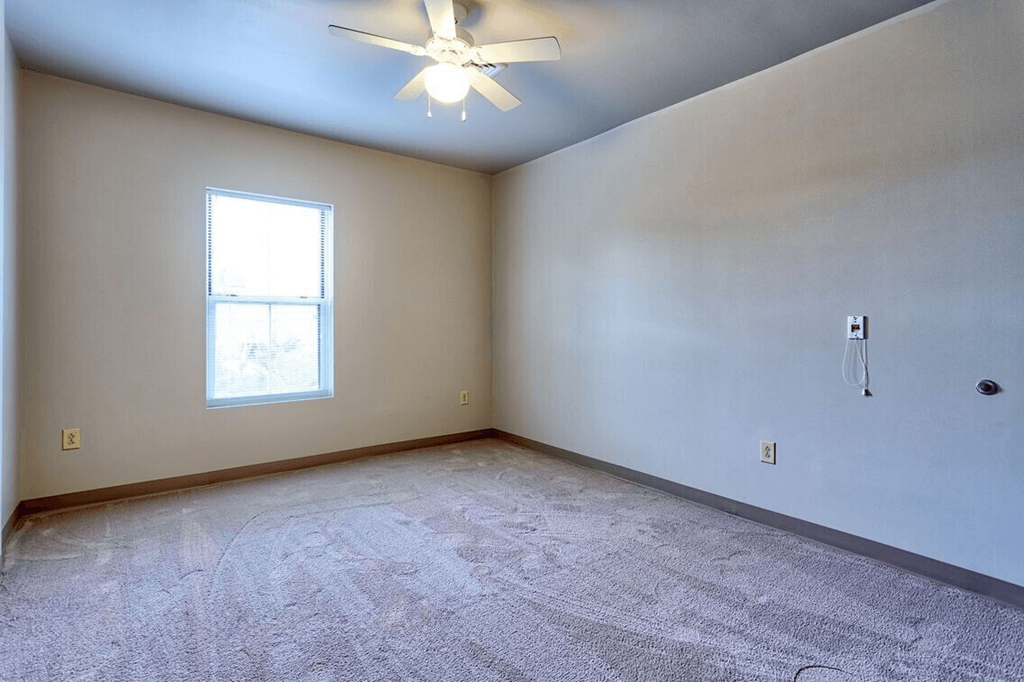 an empty room with a ceiling fan and a window
