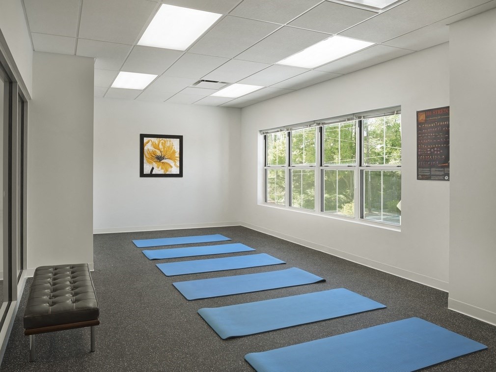 a yoga room with blue yoga mats on the floor and a bench