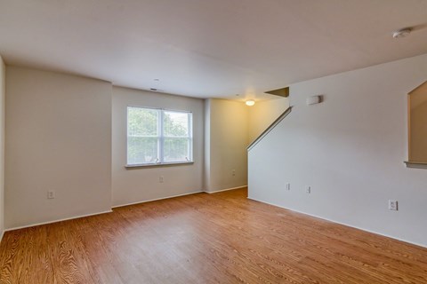 the living room and dining room of an empty house with wood flooring