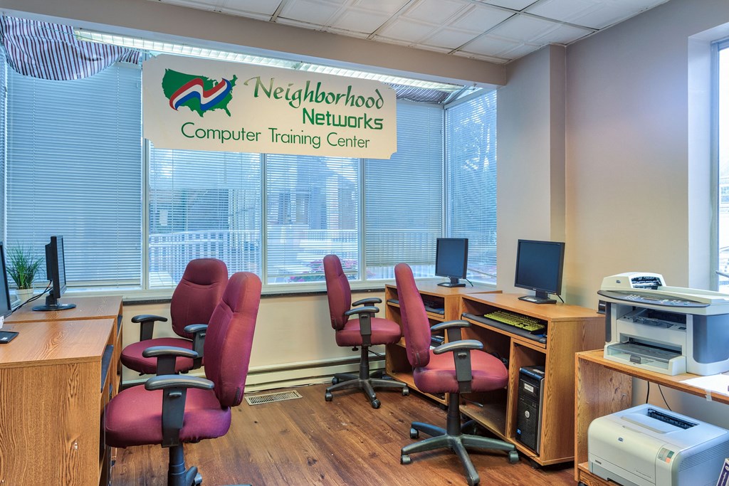 a computer room with desks and chairs and a sign on the wall