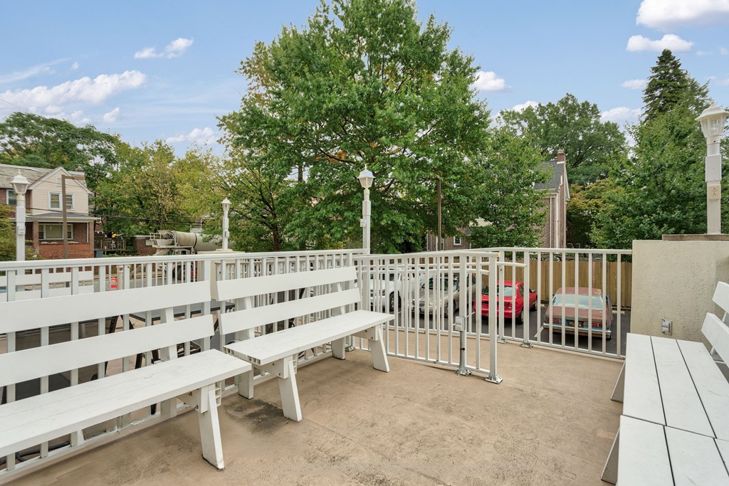 the terrace of a building with benches and a white fence