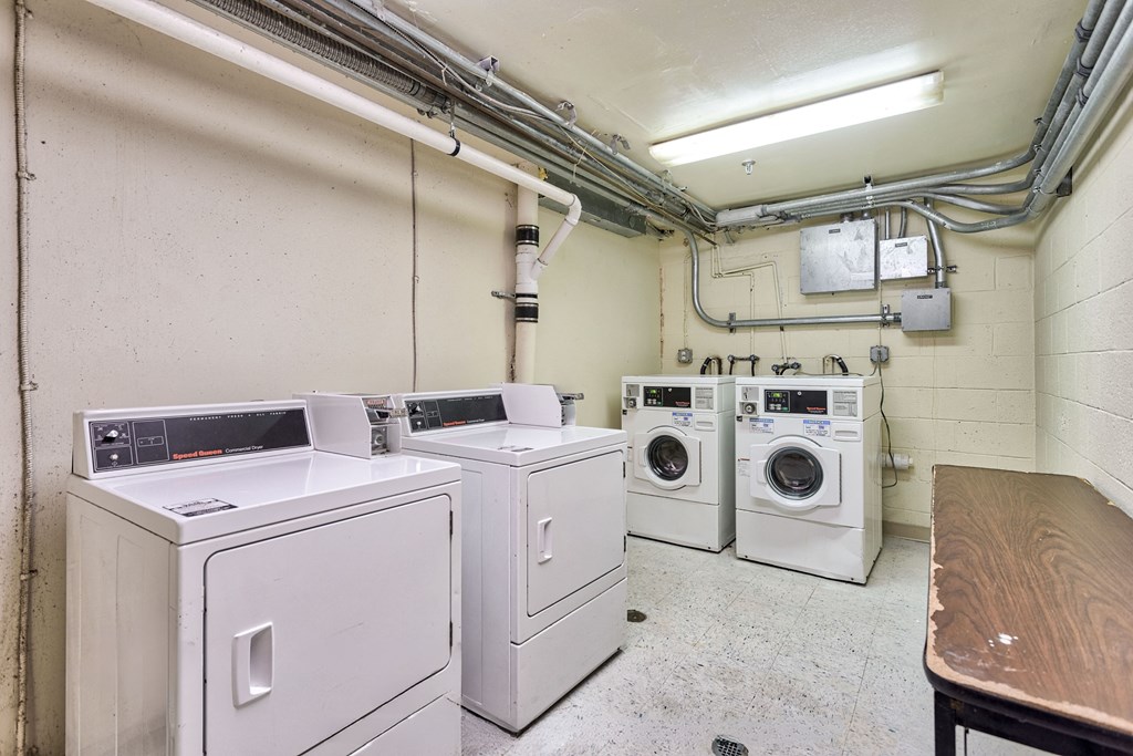 a laundry room with four washing machines and a table