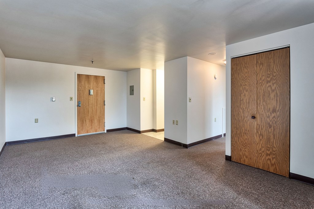 an empty living room with white walls and a wooden door