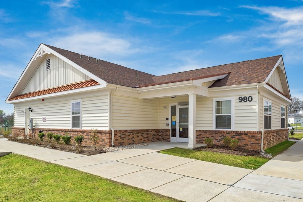 the front of a white house with a sidewalk and grass