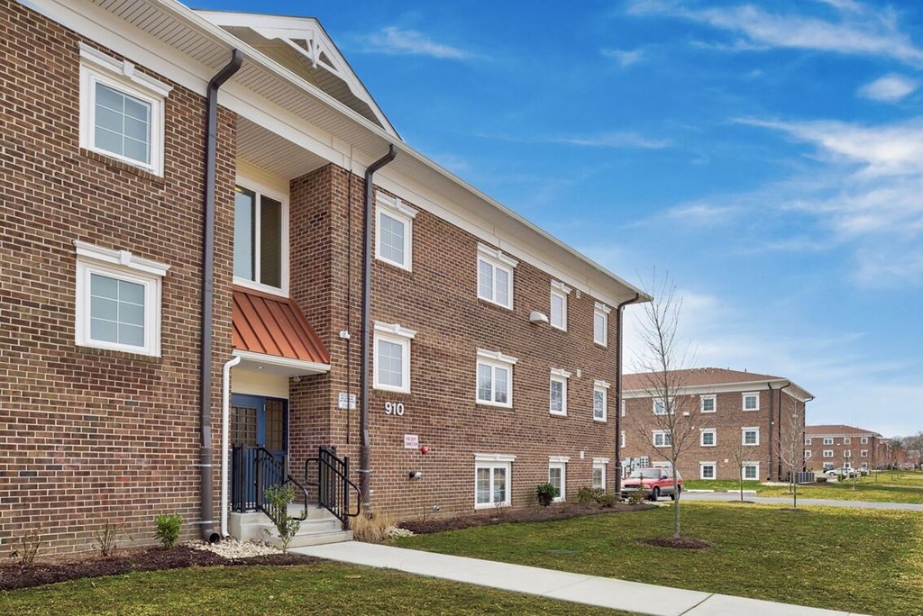 the outlook of a brick apartment building with a sidewalk
