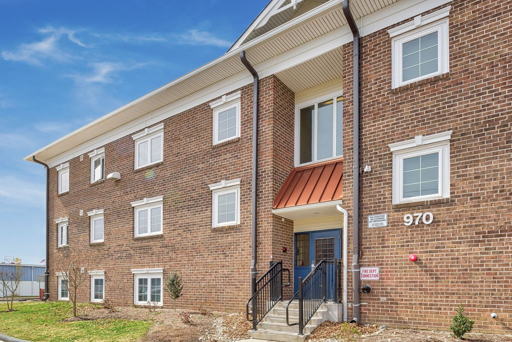 a brick apartment building with a porch and stairs