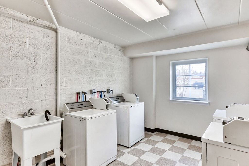 a laundry room with washing machines and sinks and a window