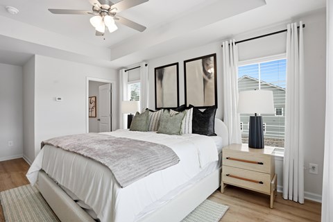 A bedroom with a large bed, a ceiling fan, and a window with curtains.
