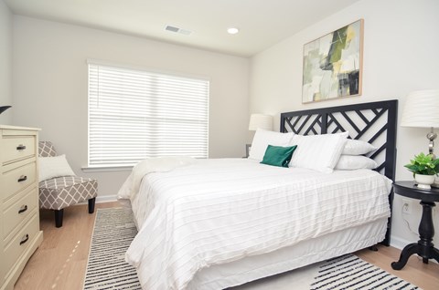 A bedroom with a large bed and a small table with a plant on it.