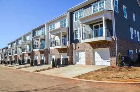 A row of modern townhouses with balconies and garages.