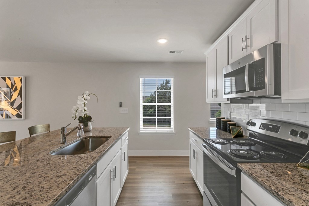 an open kitchen with granite counter tops and white cabinets