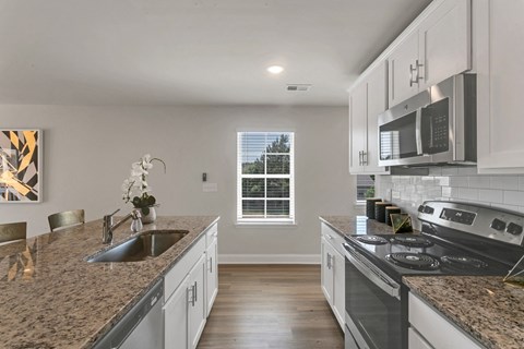 an open kitchen with granite counter tops and white cabinets