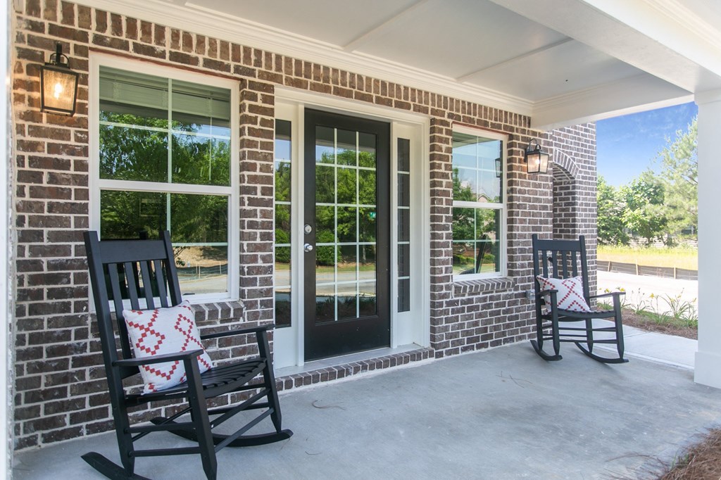 two rocking chairs on the porch of a brick house