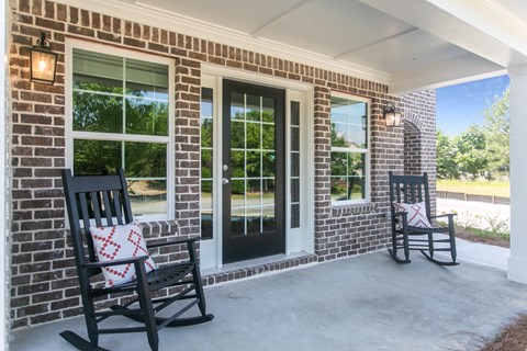 two rocking chairs on the porch of a brick house