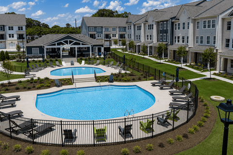 A large swimming pool surrounded by lounge chairs and a fence.