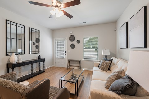 A living room with a glass coffee table and a white couch.