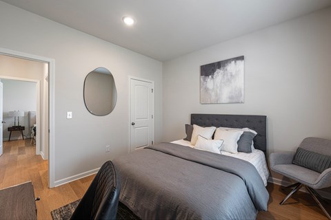 A bedroom with a large bed and a chair.