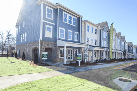 A row of new houses with a green lawn in front.