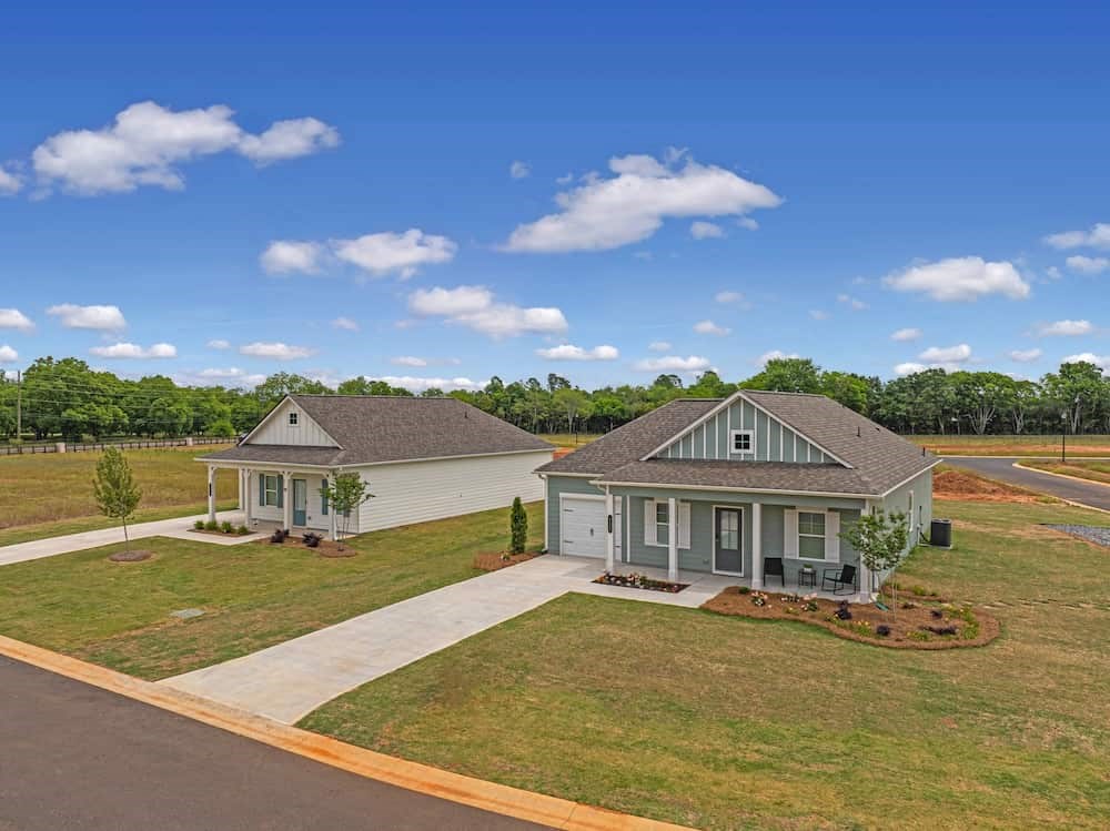 A house with a grey roof and a white garage door is surrounded by a well-maintained lawn.