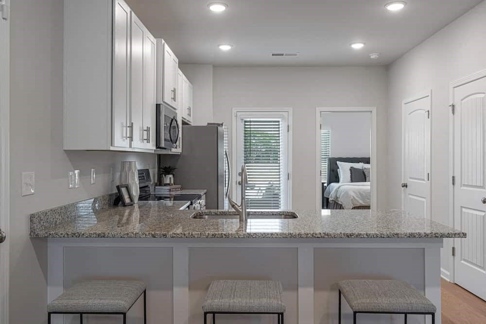 A kitchen with granite countertops and white cabinets.