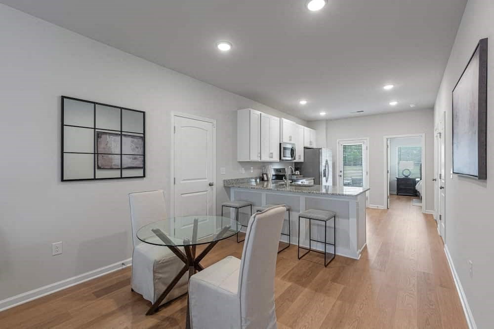 A modern kitchen with a glass table and white chairs.