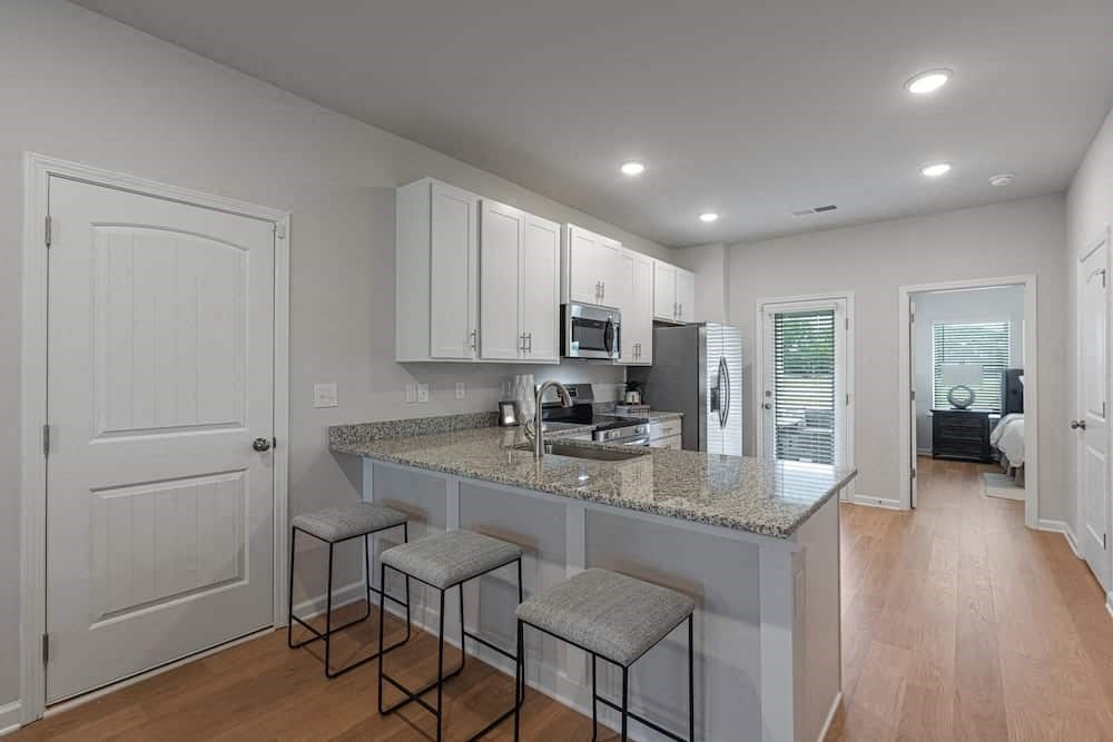 A kitchen with a granite countertop and bar stools.