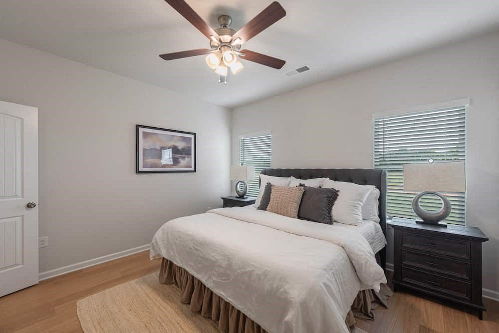 A bedroom with a bed, nightstand, and a ceiling fan.