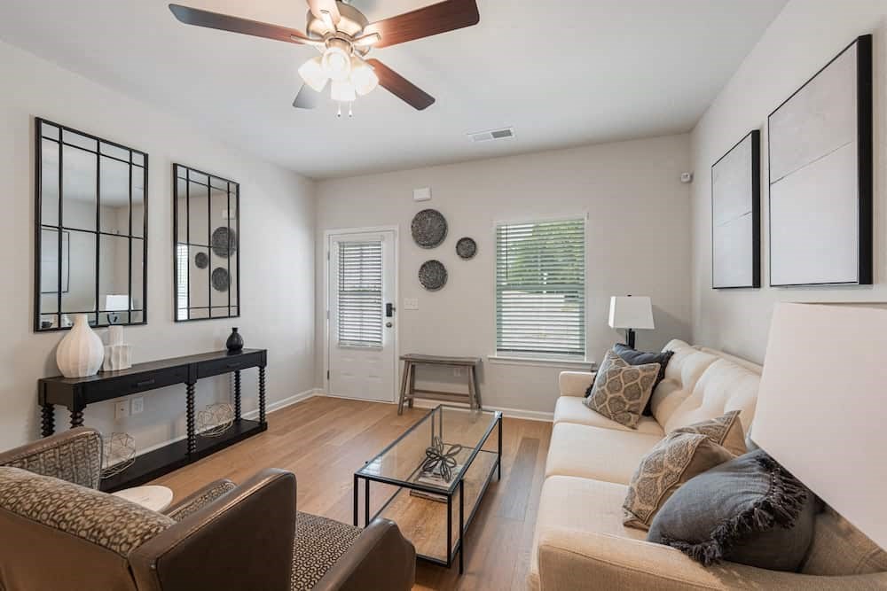 A living room with a glass coffee table and a white couch.