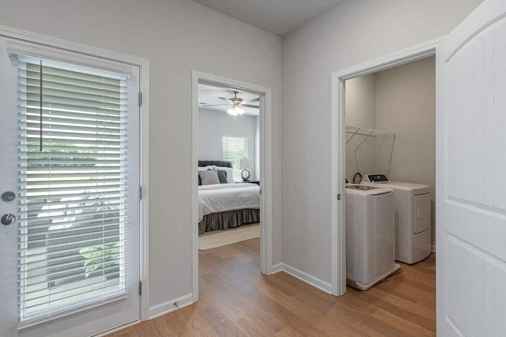 A white bedroom with a bed, dresser, and window.