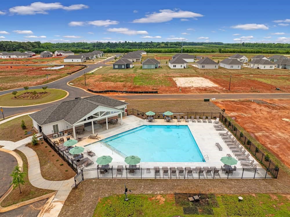 A large swimming pool surrounded by a fence and lounge chairs.
