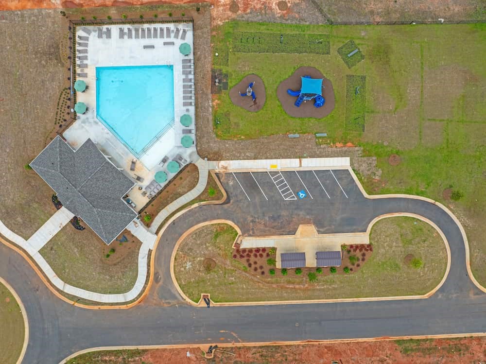 A large swimming pool is surrounded by a grassy area and a building.