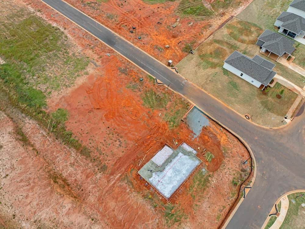 A house under construction in the middle of a field.