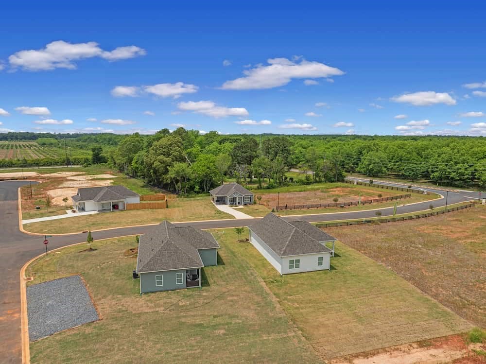 A bird's eye view of a residential area with houses and a curved road.