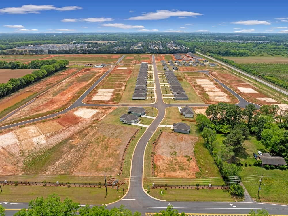 A large open field with a winding road and a few buildings.