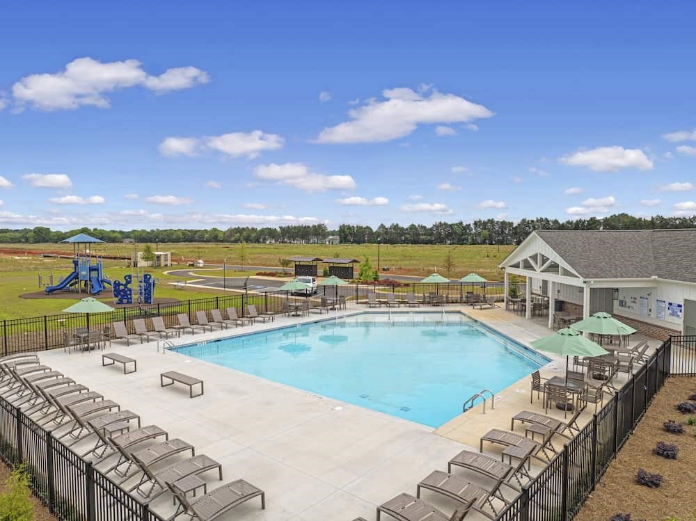 A large outdoor swimming pool surrounded by lounge chairs and umbrellas.