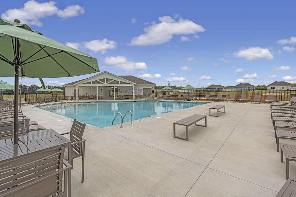 A pool area with sun loungers and a green umbrella.