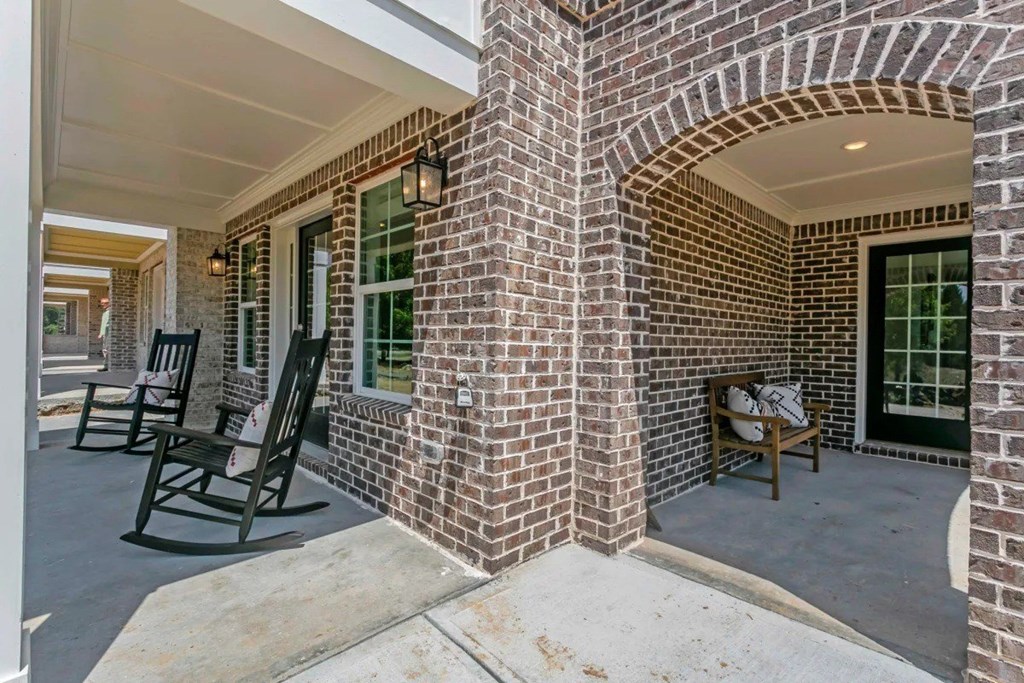 A porch with rocking chairs and a brick column.