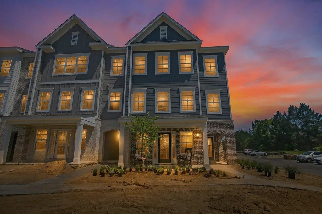 A large, modern house with multiple windows and lights on.