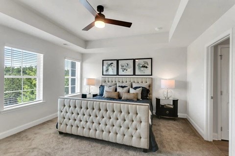 A bedroom with a large bed and a ceiling fan.