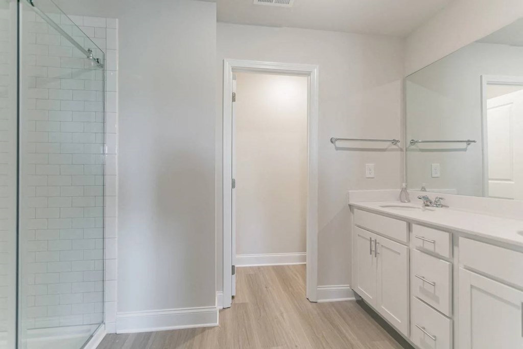 A bathroom with a white door, sink, and cabinets.